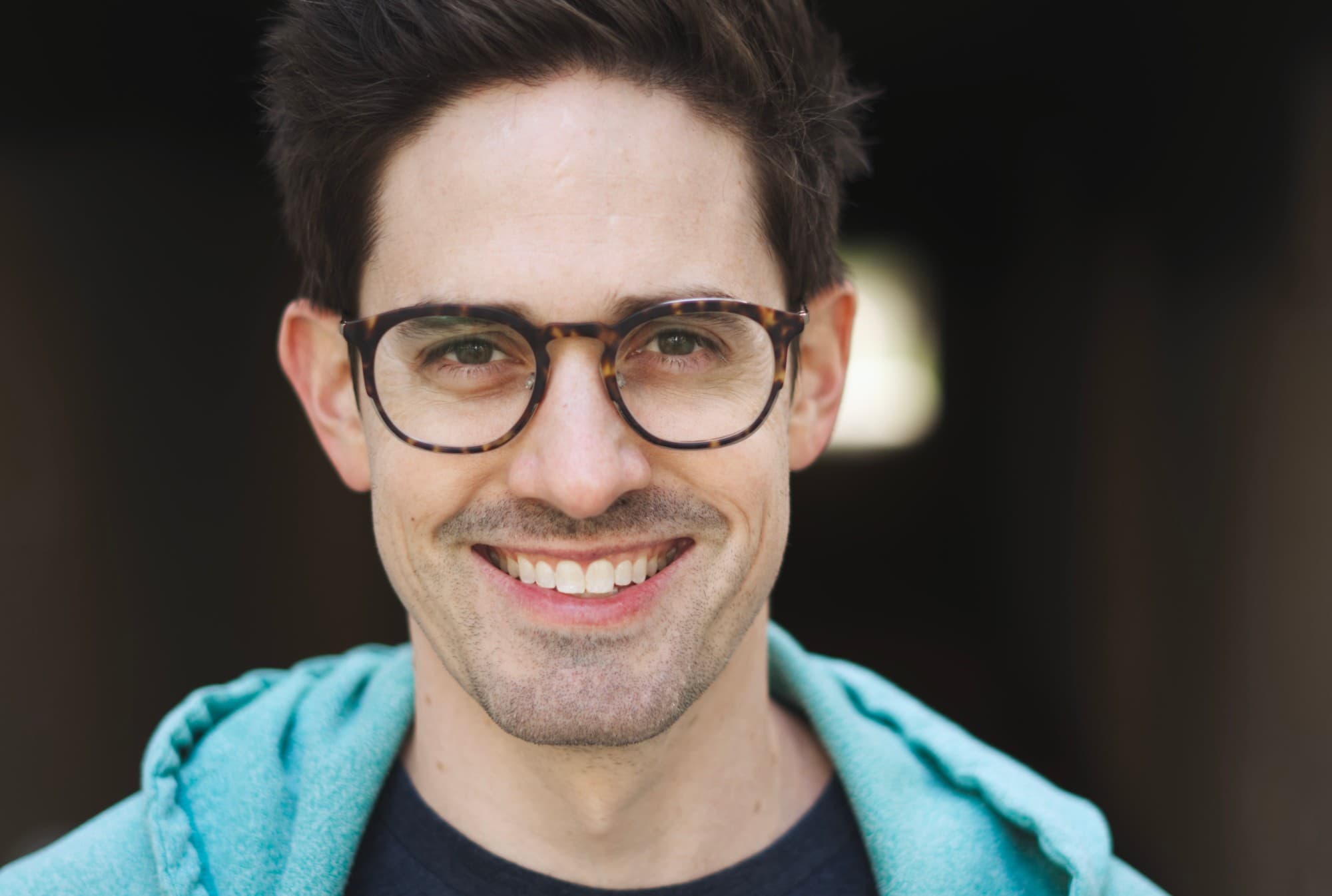 Casey O'Farrell, smiling, in glasses and a teal hoodie